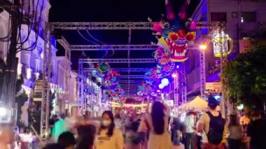 January 27,2023:Phuket old town,Thailand: timelapse landscape night view with light illumination on the colonial architecture building with crowded people in Phuket Festival 2023 night time