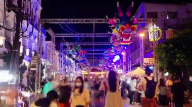 January 27,2023:Phuket old town,Thailand: timelapse landscape night view with light illumination on the colonial architecture building with crowded people in Phuket Festival 2023 night time