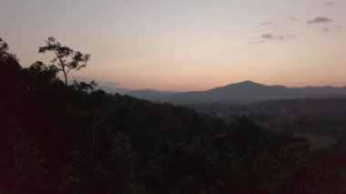 Günbatımı manzaralı dağ manzarası. Biraz bulutlu. Kış zamanı tepedeki dağdan günbatımına doğru gökyüzüne karşı dağ ormanı silueti.