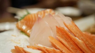 Bir kase taze saşimi taze çiğ Japon yemeğinin yanına yaklaşırken yemek çubuklarıyla buzdan sashimi, restoranda Japon yemeği.