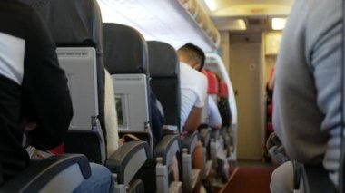 Rahatlarken yolcu dolu uçak kabininin içinde dar bir koridor var. İnsanlar jet uçağıyla tanınmayan yolcularla rahat koltuklarda seyahat ediyorlar.