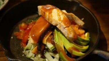 Poke kasesine ev yapımı sos dökülüyor pirinç ızgara somon avokadosu ve bezelye soslu Hawaii usulü çiğ balık salatası..