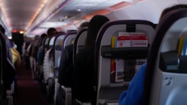 Rahatlarken yolcu dolu uçak kabininin içinde dar bir koridor var. İnsanlar jet uçağıyla tanınmayan yolcularla rahat koltuklarda seyahat ediyorlar.