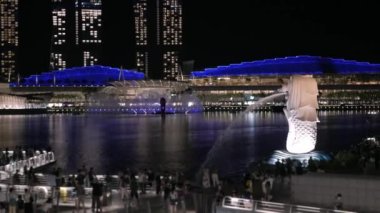 Singapur 'daki marina körfezi manzarası, Merlion heykeli, birçok turist gece vakti Singapur' un şehir merkezinde geziyor.