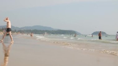 Nisan 6.2023.Phuket, Tayland. İnsanlar yaz tatillerinde tatil yaparken dinleniyorlar. Tropik bir ada olan Phuket 'te beyaz kumsal kenarında, güneşli bir günde güneşli bir günde 4K video görüntülerinde.