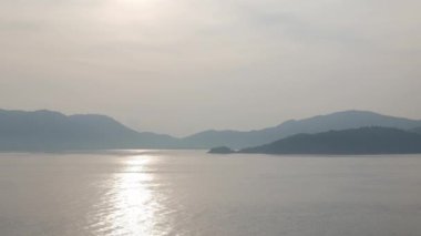 Ufkun üzerinde görünen bir adayla sakin ve güneşli bir günde usulca el sallayan mavi deniz manzaralı doğal deniz manzarası. Phuket 'teki Patong Körfezi' nde deniz.
