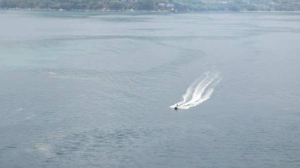 透明度の高い緑の海の中で美しい白い泡の波を作るパトンベイエリアでジェットスキーアクションエクストリームウォータースポーツをしている人々と海への眺め — ストック動画