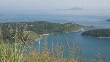 Yaz tatilinde tropikal okyanus denizi ve güneş ışığı altındaki adaların güzel doğal manzaralı deniz kıyısı manzarası yeşil çimen tarlası, Phuket, Tayland 'daki siyah kaya manzarası