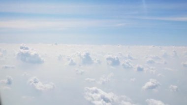 Uçakta uçarken, bulutların üzerinde uçan uçağın berrak mavi gökyüzü üzerindeki kabarık beyaz bulutun hava görüntüsü. Hava yoluyla seyahat eden uçağın penceresinden görünüm, doğal arka plan konsepti