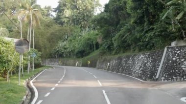 natural view of the local road outdoor through the tropical rain tree forest in Kuala lumpur,Malaysia suburb under sunshine day , southeast asia landscape road