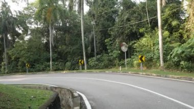 natural view of the local road outdoor through the tropical rain tree forest in Kuala lumpur,Malaysia suburb under sunshine day , southeast asia landscape road