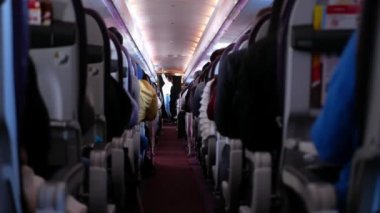 Rahatlarken yolcu dolu uçak kabininin içinde dar bir koridor var. İnsanlar jet uçağıyla tanınmayan yolcularla rahat koltuklarda seyahat ediyorlar.