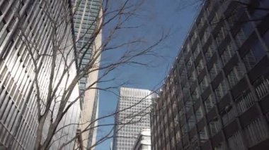 Şehir ticaret bölgesindeki modern ofis, gökdelen ve finans binalarına bak. Gökyüzüne kadar uzanan, arka planda berrak gökyüzü olan modern cam binalara bakıyorum.