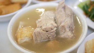 Yemek saatinde bir kase bak kut teh 'den domuz kaburgası kapmak için yemek çubukları kullanırdım. Asya Singapur Malezya usulü sıcak çorba. Gelenek kültürü Asya tekil yiyecekleri