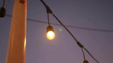 Arkaplanda günbatımı gökyüzü olan kutba asılı olan ampule seçici bir şekilde odaklan