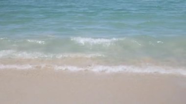 Turkuaz deniz dalgaları, yaz tatili için deniz manzarası olan beyaz kum pürüzsüz plajlara vurur.