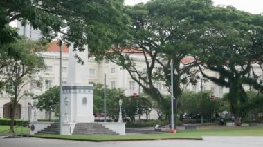 Mayıs 2023, Singapore. Singapur şehrinin merkezindeki yeşil parka bakın. Parkta dikilitaş heykel ve gündüz dinlenen insanlar var. Singapur 'un megaşeliğindeki huzurlu yeşil park