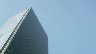 Düşük açılı, modern cam cephe ofis binasının, finans bölgesinde mavi gökyüzü olan gözlüklü, cam aynalı, yakın açılı, sabit açılı görüntüsü.