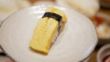Japon usulü tatlı omletle Japon usulü suşi kapmak için çubuk kullanarak geleneksel tabakta Japon yemeği.