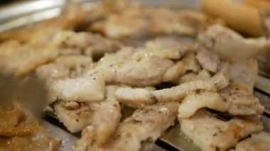 Izgarada ızgara ızgara Kore domuz eti pişirirken yakın plan. Izgarada domuz göbeği, tavada samgyupsal, tavada domuz eti pişirme, açık büfede Kore usulü domuz eti barbeküsü.