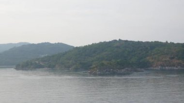 Ufkun üzerinde görünen bir adayla sakin ve güneşli bir günde usulca el sallayan mavi deniz manzaralı doğal deniz manzarası. Phuket 'teki Patong Körfezi' nde deniz.