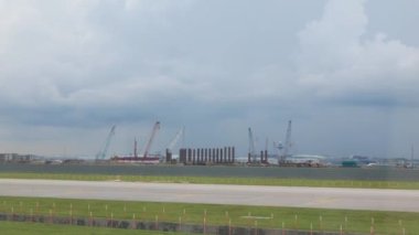 Singapur Havaalanı 'nın inşaat alanı. Havaalanı terminali binalarının ve hava trafik kontrol kulesinin arka planına sahip. Uçak penceresinden taksicilik yapan uçağa binerken...