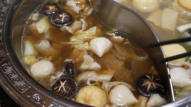 中国風スパイシーな鍋料理を調理しながらキノコ豚のスライスと野菜の熱い沸騰中国語スタイルのスープベース 家庭料理鍋家族の時間 — ストック動画