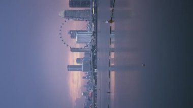Singapur Ufuk Çizgisi şehrinin modern ofis gökdelenleri ile Singapur Nehri 'nin kıyısındaki dikey videosu günbatımında merkez iş bölgesinde yüksek gökdelen finans binaları..