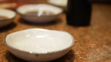 Japon restoranında Japon yemeği daldırmak için Shoyu soya sosu dökerken seramik tabağa seçici bir şekilde odaklan. Geleneksel Japon restoranı.