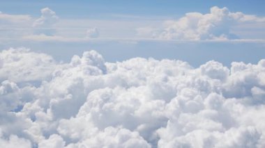 Uçakta uçarken, bulutların üzerinde uçan uçağın berrak mavi gökyüzü üzerindeki kabarık beyaz bulutun hava görüntüsü. Hava yoluyla seyahat eden uçağın penceresinden görünüm, doğal arka plan konsepti