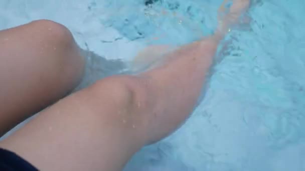 在炎炎夏日的阳光下 游泳池边清澈的蓝水衬托着纤细的女性腿 在游泳池边休息 晒日光浴 — 图库视频影像