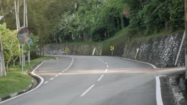 natural view of the local road outdoor through the tropical rain tree forest in Kuala lumpur,Malaysia suburb under sunshine day , southeast asia landscape road