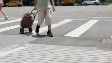 Yazın kalabalık insanlar caddeyi geçerken kavşaktaki asfalt sokağa alçak açılı bir bakış açısı. Trafiğin en yoğun olduğu saatte yayanın ayakları kesişir.