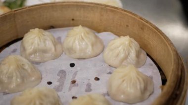 Xiaolongbao hamur köfteleriyle dolu bir bambu tepsisine bakın. Sıcak akıntılı Tayvan yemeği. Masadaki bambu budan xiaolongbao almak için çubuk kullanın.