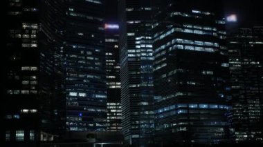 Modern ofis gökdeleni finans binaları gece vakti şehrin iş bölgesinde ışıklandırılmış. 4k modern şehirde modern camlara finansal modern binalara bakıyorum.