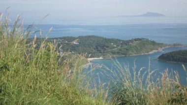Yaz tatilinde tropikal okyanus denizi ve güneş ışığı altındaki adaların güzel doğal manzaralı deniz kıyısı manzarası yeşil çimen tarlası, Phuket, Tayland 'daki siyah kaya manzarası