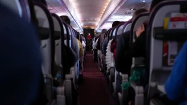 Rahatlarken yolcu dolu uçak kabininin içinde dar bir koridor var. İnsanlar jet uçağıyla tanınmayan yolcularla rahat koltuklarda seyahat ediyorlar.