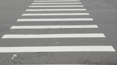 İnsanlar gündüz yaya geçitlerinde yürürken, zebra kavşağındaki asfalt sokağa alçak açılı görüş.