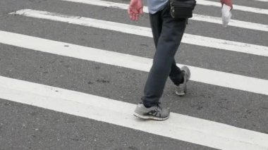 İnsanlar gündüz yaya geçitlerinde yürürken, zebra kavşağındaki asfalt sokağa alçak açılı görüş.