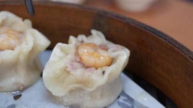 Tayvan geleneksel yemeklerini sıcak akıntıyla pişirirken aynı zamanda Xiaolongbao 'yu masadaki bambu şeritlerinden topluyor.