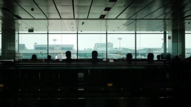 Ağustos 2,2023. Cingapore Changi Havaalanı. Yolcular hareket halindeki yürüyen yürüyen merdivende, silüet içinde Singapur Havaalanı 'nda uçuş bekleyen birçok yolcuyla birlikte yürüyorlar.