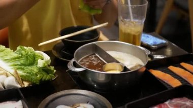 Shabu sosunu kaynayan sıcak tencere çorbasında pişirirken bir sürü sebzeyle birlikte yakın çekim yapın. Japon Asya usulü lezzetli, sağlıklı, Shabu yemeği.