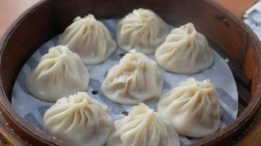 Xiaolongbao hamur köfteleriyle dolu bambu tepsisine bak, Tayvan geleneksel yemekleri bambu buharlı buharlı sıcak akarsu Çin usulü restoranın masasına yerleştirilmiş.