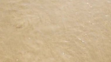 Beyaz kumsal yüzey dokusunu deniz dalgalarıyla görmek yaz güneşli bir günde sahile vurdu, dalgalar beyaz köpük dalgalarıyla kıyıya doğru sürüklendi, yaz tatili arka planında 4k videosu çekildi.