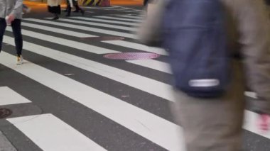 Crowd of pedestrians crossing a city street in low angle view of legs and feet of crowded people society and city life concept in feet lower view closeup in tokyo city nigh time