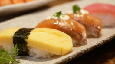 Öğle yemeği saatinde yemek çubuğuyla bir tabak suşiyle Japon yemeği yemeye odaklan. Yemek saatinde yemek çubuğuyla suşiyi tabaktan al. Modern geleneksel Japon yemekleri..