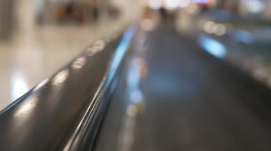 Hareket halindeki yürüyen yürüyen merdivenin tırabzanı için seçici odaklı pov havaalanı kalkış terminali terminali koridorunda seyahat için çıkış kapısına hareket ederken