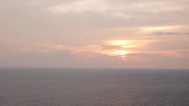 Altın denizi, vanilyalı gökyüzü ve okyanus yüzeyinde palmiye ağaçlarının silueti olan tropikal bir uçurumda güzel bir günbatımı, doğa denizi yaz mevsimi 4K 'da tropikal günbatımı