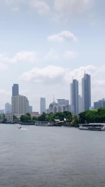 川の水上ボートの輸送とバンコク市のスカイラインの背景を持つカオプラヤ川の垂直なタイムラプスパノラマ景色は 昼間の中央地区エリアの中で多くの高層ビルを誇っています — ストック動画