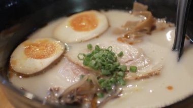 Japon restoranındaki Japon usulü ramen ya da Japon restoranındaki zengin aromalı erişte çorbasını ramen yemek için pirzola çubuğu kullanarak yakın çekim yapın.